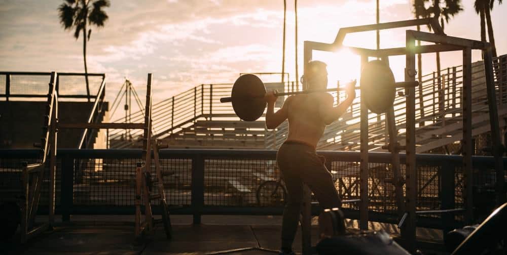 Man doing squats during sunset for the optimal glutes volume